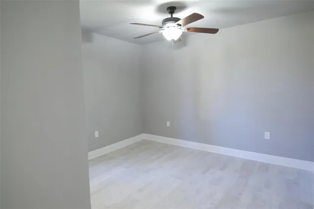 an empty room with a fan & a window