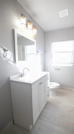 a bathroom with a toilet a sink a mirror and a window