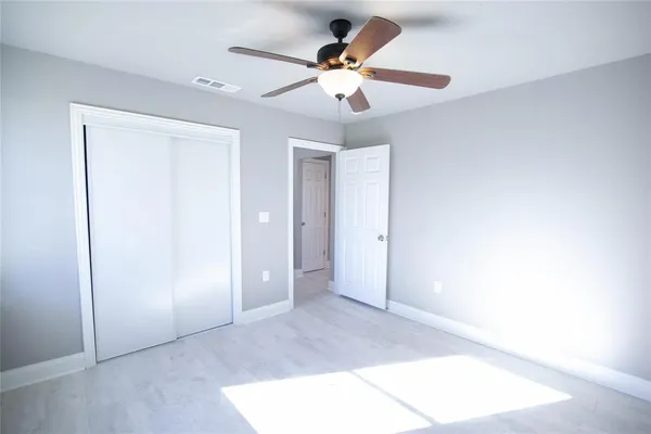 an empty room with closet and a ceiling fan