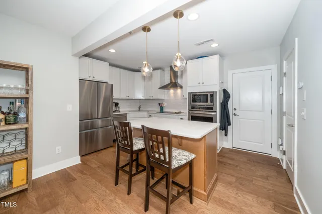 a kitchen with stainless steel appliances a refrigerator a stove a sink and chairs