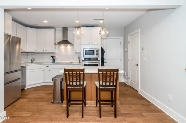 a kitchen with stainless steel appliances granite countertop a white table and chairs