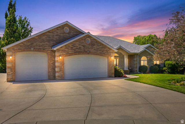 Brick veneer facade with arched garage doors, a two-car garage, and a concrete driveway