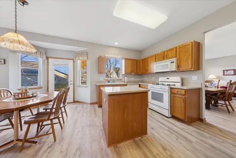 a kitchen with stainless steel appliances granite countertop a stove top oven a sink dishwasher a dining table and chairs with wooden floor