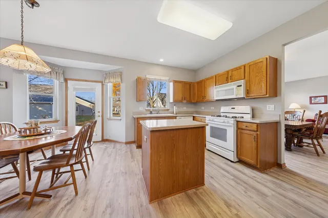 a kitchen with stainless steel appliances granite countertop a stove top oven a sink dishwasher a dining table and chairs with wooden floor