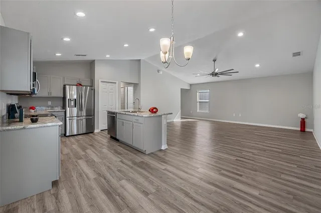 a kitchen with granite countertop a refrigerator a sink dishwasher stove top oven and cabinets