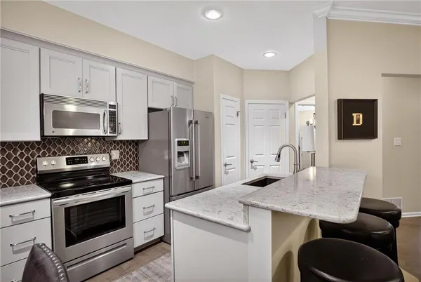a kitchen with granite countertop kitchen island stainless steel appliances a stove refrigerator sink and cabinets