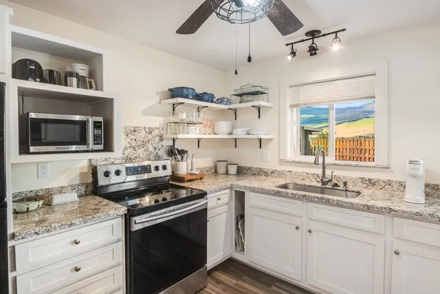 a kitchen with stainless steel appliances granite countertop a sink a stove and a microwave