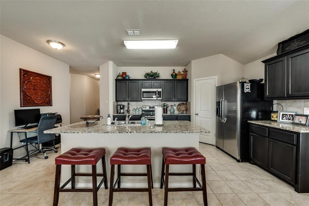 649 Clearbrook Street Azle, TX 76020 - Photo 4 of 28 a kitchen with stainless steel appliances kitchen island granite countertop dining table chairs cabinets and a sink