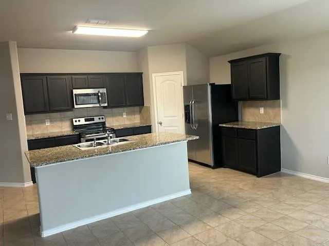 a kitchen with a stove a counter top space and living room view