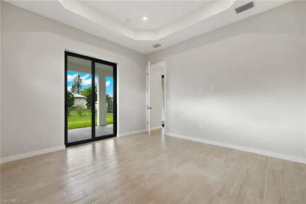 a view of an empty room with window and wooden floor