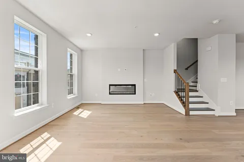 a view of an empty room with stairs and wooden floor