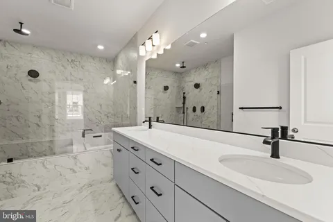 a bathroom with a double vanity sink mirror and shower