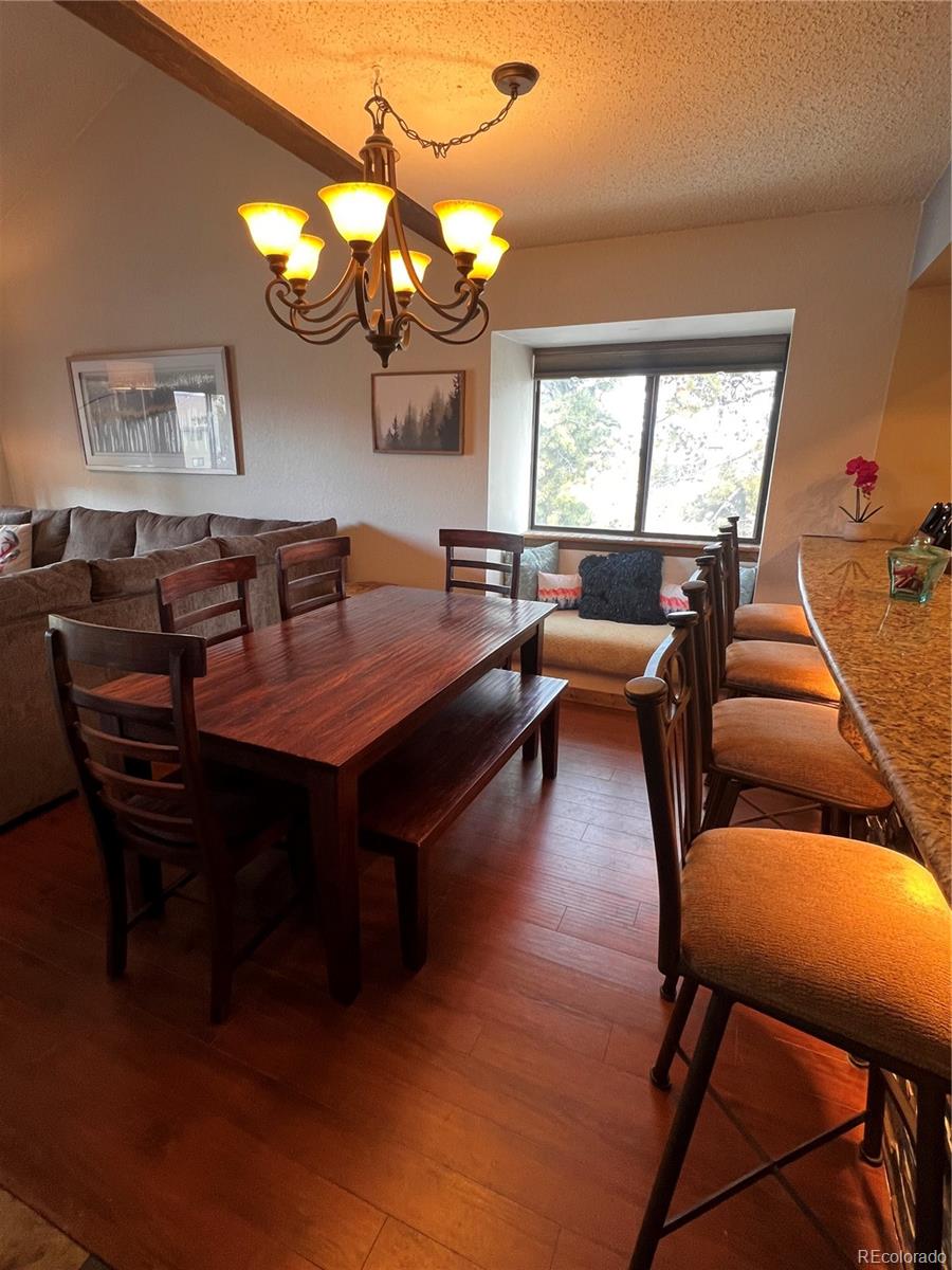 317 County Road 832, Unit 2412 Fraser, CO 80442 - Photo 4 of 17 a dining room with wooden floor a chandelier a wooden table and chairs