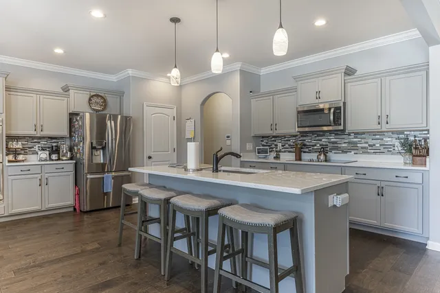 a kitchen with kitchen island granite countertop a sink a center island stainless steel appliances and cabinets