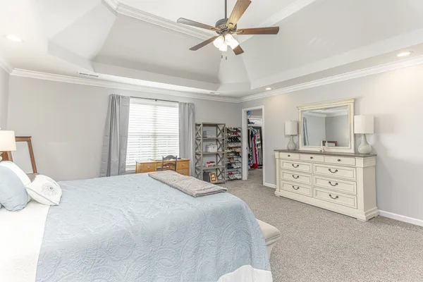 a bedroom with a bed a dresser and a large window