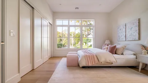 a bedroom with a bed lamp and a large window