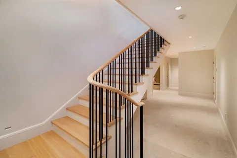a view of staircase with wooden floor and white walls