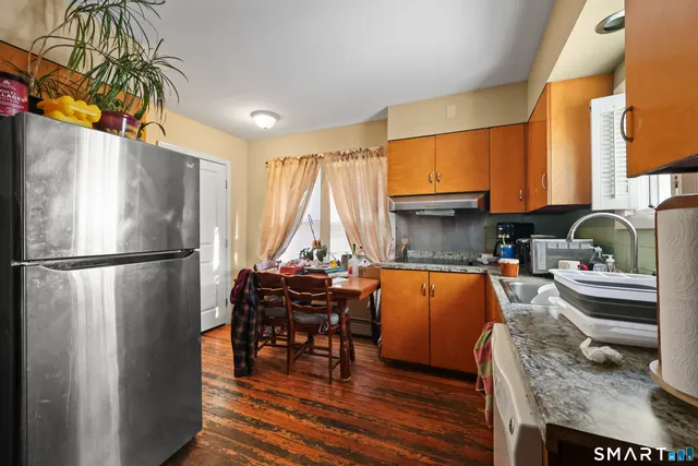 a kitchen with stainless steel appliances granite countertop a refrigerator a stove and a dining table with wooden floor