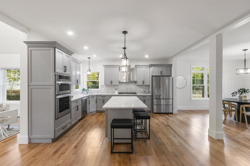 50 Azalea Circle Reading, MA 01867 - Photo 12 of 41 a kitchen with a center island wooden floor stainless steel appliances and windows