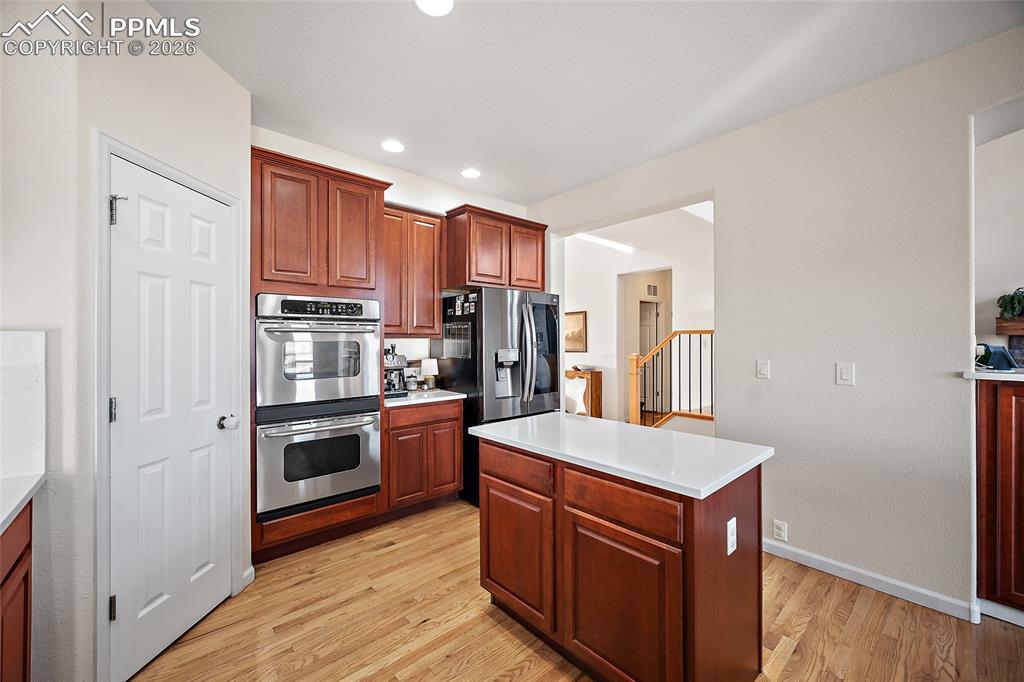 9393 St.George Road Peyton, CO 80831 - Photo 12 of 49 a kitchen with stainless steel appliances granite countertop a refrigerator a stove and a sink with wooden floor