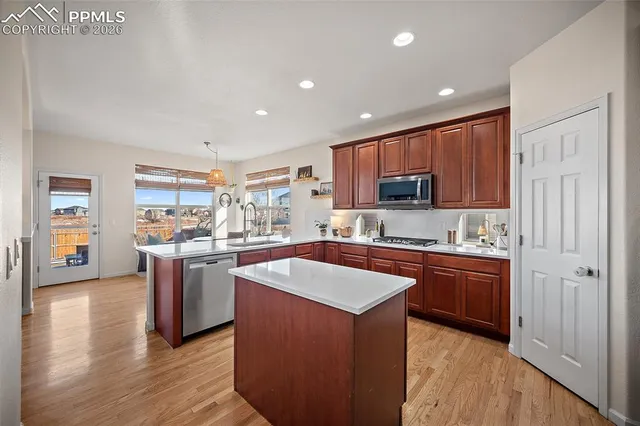 a kitchen with stainless steel appliances granite countertop a stove top oven a sink dishwasher and a refrigerator with wooden floor