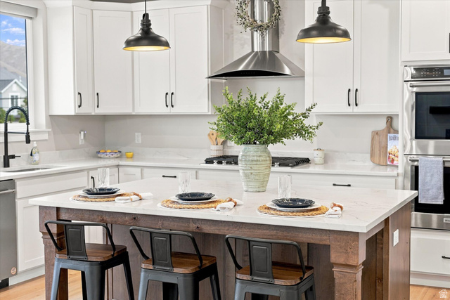 754 West 400 North Mapleton, UT 84664 - Photo 17 of 86 White shaker cabinetry, light-toned countertops, stainless steel appliances, a large wood-finish island, and pendant lighting.