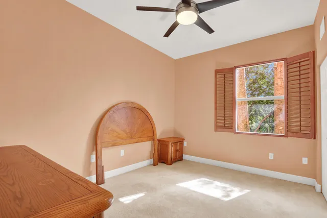 an empty room with ceiling fan and windows