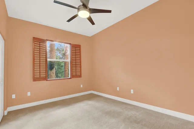 an empty room with a window and a ceiling fan