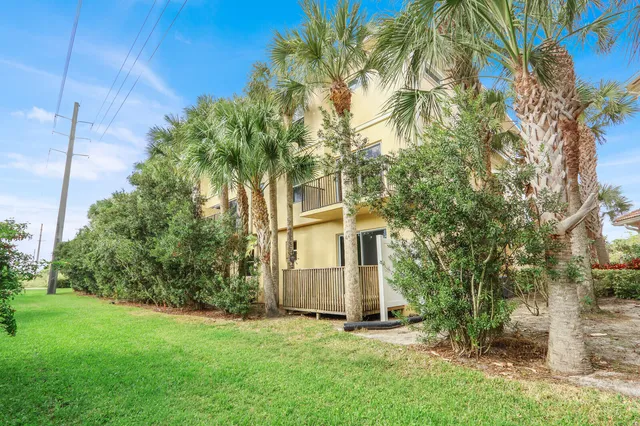 a view of a white house with a big yard and large trees