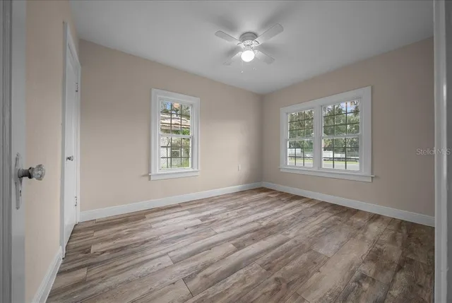 a view of empty room with wooden floor and fan