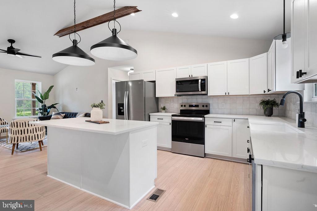 26332 Old Pitts Road Ruther Glen, VA 22546 - Photo 12 of 35 a kitchen with stainless steel appliances a stove a sink dishwasher a refrigerator and white cabinets with wooden floor