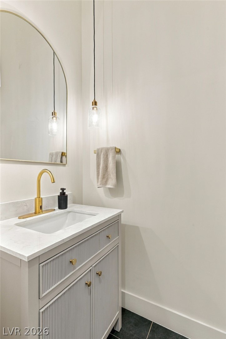 324 Wanda Road Henderson, NV 89002 - Photo 26 of 96 Elegant gold hardware pairs beautifully with stone counters and contemporary textured cabinetry in this washroom.