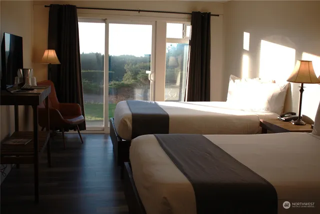 a bedroom with two beds and a large mirror next to a window
