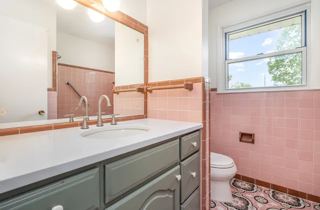 a bathroom with a granite countertop toilet sink and mirror