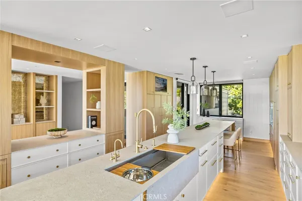 a room with stainless steel appliances kitchen island granite countertop a sink and wooden cabinets