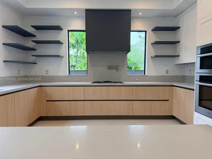 a large kitchen with kitchen island granite countertop a large window and a sink