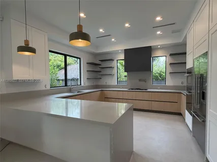 a large white kitchen with granite countertop a refrigerator and a sink