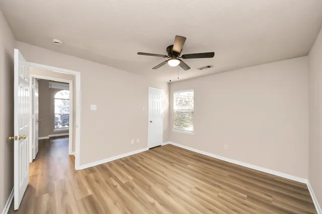 a view of empty room with wooden floor and fan