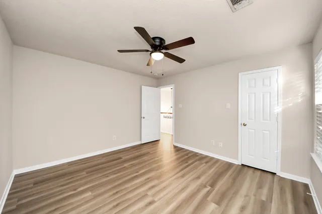 a view of empty room with wooden floor and fan