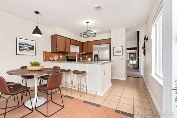 a view of kitchen with stainless steel appliances granite countertop dining table chairs cabinets and a sink