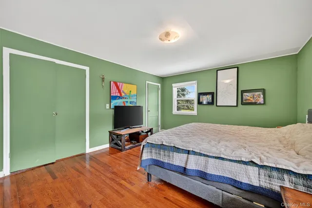 a bedroom with a bed and dresser with wooden floor