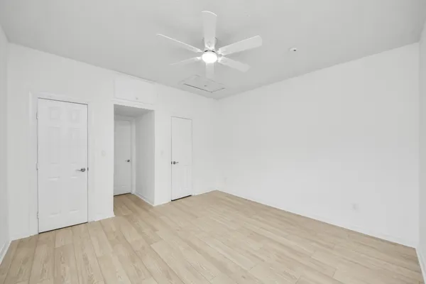 an empty room with a window and ceiling fan