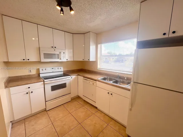 a kitchen with granite countertop white cabinets and white appliances