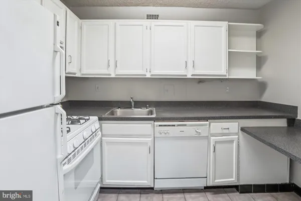 a kitchen with granite countertop white cabinets and white appliances