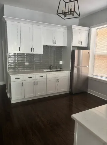 a kitchen with granite countertop a refrigerator a sink dishwasher a stove and white cabinets