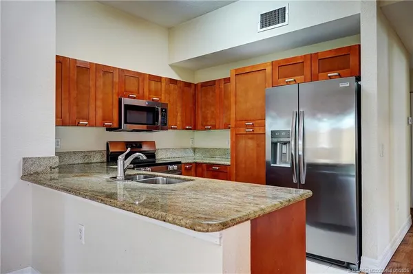 a kitchen with stainless steel appliances granite countertop a refrigerator a stove top oven a sink and dishwasher