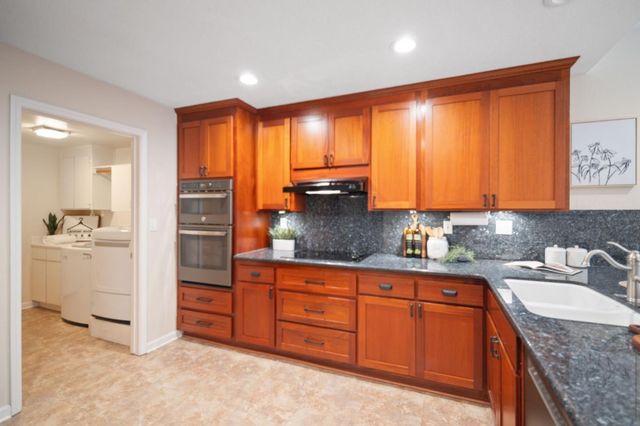 a kitchen with stainless steel appliances granite countertop a sink a stove and cabinets