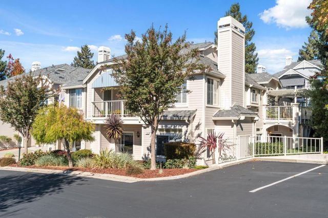 a front view of a house with a garden and tree