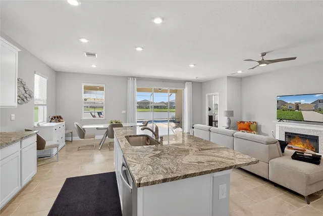 a living room with furniture kitchen view and a large window