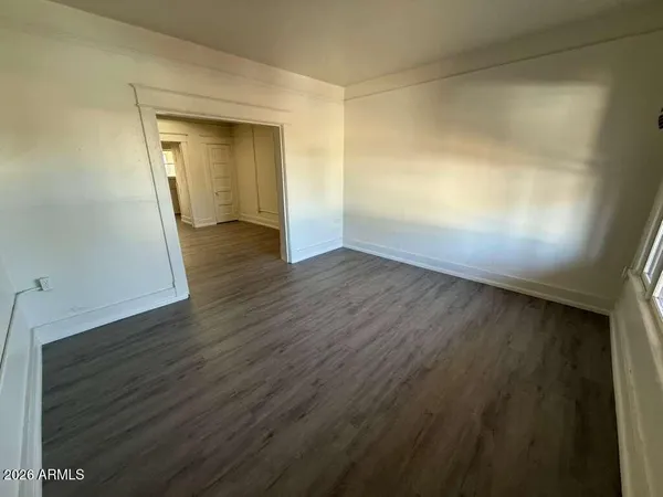an empty room with wooden floor and mirror
